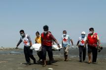 Members of the Myanmar Red Cross carry a dead body of a driver from a boat in Sittwe, Rakhine State on April 21, 2020 killed while delivering test kits for COVID-19 coronavirus. Photo: AFP