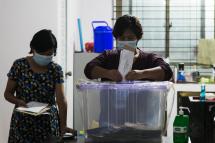 A medical volunteer (R) casts her ballot in a mobile polling station inside a Covid-19 coronavirus medical center in Yangon on October 29, 2020. Photo: Sai Aung Main/AFP