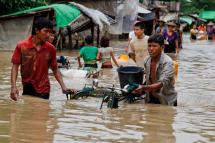 A picture made available on 04 August 2015 shows people carrying their belongings as they pass through a flooded street in Min Pyar township of Rakhine State, Myanmar, 02 August 2015. Photo: Nyunt Win/EPA
