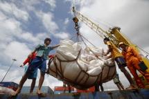 Workers use crane as they unload chemical-fertilizer bags from a ship at Asia World port in Yangon. Photo: Lynn Bo Bo/EPA