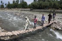 A doctor and health workers cross a wooden bridge during a Covid-19 vaccination drive in a village in Tral, some 35 km south of Srinagar, the summer capital of Indian Kashmir, 05 June 2021. Photo: EPA