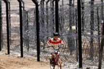 An Indian boy rides a bicycle near the Indo-Burma International border fencing in Moreh, a border town in India’s northeastern state of Manipur bordering Burma’s Tamu town, 12 June 2011. Photo: EPA
