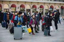 Passengers wearing face masks walk with their luggage in front of the Beijing Railway Station in Beijing, China, 10 January 2023. Photoe: EPA