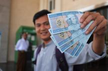 A man holds new Myanmar kyat banknotes with a portait of the late general Aung San, outside the Myanmar Economic Bank in Naypyidaw on January 7, 2020. Photo: AFP