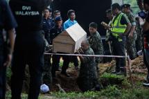 Malaysian authorities hold a coffin containing remains believed to be of Rohingyas at Pokok Sena, Kedah, Malaysia, 22 June 2015. On May 25 police found more than 100 skeletal remains of victims of human trafficking syndicates in graves at the temporary detention camp at Bukit Wang Burma in Wang Kelian on Perlis state. Photo: EPA

