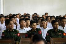 (File) Myanmar boys wearing white shirts, who were released from Myanmar army, sit behind Myanmar military officers during the ceremony on handover discharged minor to parents (or) guardian in Yangon. Photo: Lynn Bo Bo/EPA