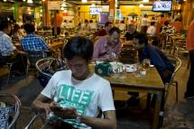Customers check social media sites from their mobile phone while at a restaurant in Yangon. Photo: ROMEO GACAD/AFP
