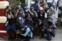 Visual journalists take cover near the entrance of a monastery where military supporters are gathering as they are attacking the protestors and medias and residents, in Yangon, Myanmar, 18 February 2021. Photo: EPA
