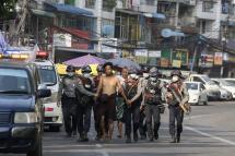 (File) In this file photo taken on February 26, 2021, police march with a resident arrested during a crackdown on protesters holding rallies against the military coup in Yangon. Photo: AFP