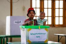 (File) A woman wearing Thanakha, a yellowish-white traditional cosmetic paste, on her cheeks carries her child as she casts her vote for by-elections at a polling station of Hlaing Thar Yar township in Yangon, Myanmar, 01 April 2017. Photo: Lynn Bo Bo/EPA