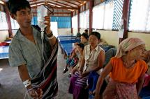 A Karen man (L) holds his saline solution walks past a group of Karen women as they wait for medical treatment at Paw Bu La Hta clinic in Kow Poe Kee village, Karen state, Myanmar, 03 April 2008. Photo: Rungroj Yongrit/EPA
