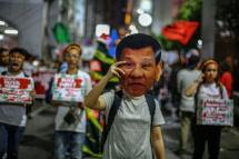 A human rights advocate holds up a mask featuring Philippine President Rodrigo Duterte during a rally in Manila (AFP Photo/Maria TAN) 