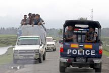 People travel by car as police vehicle drive pass in Maungdaw township, Rakhine State. Photo: Nyein Chan Naing/EPA