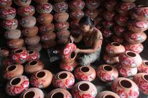 A female worker paints a pot in Twantay, about 50 km south of Yangon. Photo: Khin Maung Win/AFP
