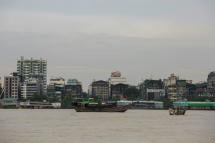 Residential and commercial buildings by the river banks as boats sail across the Yangon River. Photo: Sai Aung Main/AFP