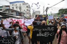 Protesters hold banners and make the three-finger salute as they take part in a demonstration against the military coup and to mark the anniversary of 1962 student protests against the country's first junta in Yangon. Photo: AFP