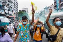 A protester holds a flare as others make the three-finger salute during a demonstration against the military coup in Yangon on June 22, 2021. Photo: AFP