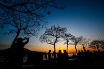 People take photographs of sunset at a riverside park in New Taipei City, Taiwan. Photo: EPA