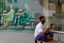 A man wearing a face mask, as part of efforts to halt the spread of the COVID-19 coronavirus, looks at his phone in Yangon on April 10, 2020. Photo: Sai Aung Main/AFP
