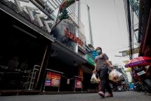 A woman wearing a protective mask walks past closed bars in a nearly deserted entertainment street in Bangkok, Thailand, 20 March 2020. Photo: EPA