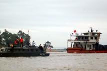 (File) Thai police patrol ship (L) guards a Chinese cargo ship (R) arriving to Chiang Saen port, Chiang Rai province, northern Thailand, 11 December 2011. Photo: EPA