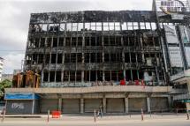 A man walks pass bear a burnt down shopping mall owned by military at downtown area of Yangon, Myanmar, 22 April 2021. Photo: EPA