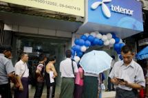 This file photo shows people queuing to buy Telenor's sim card at a local mobile shop in Yangon. The company is selling its business and leaving Myanmar. Photo: AFP