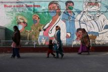 Women walk past a graffiti amidst the spread of the coronavirus disease (Covid-19) in New Delhi, India. Photo: Reuters
