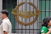 Pedestrians walk past a logo of the Asian Development Bank (ADB) displayed outside its headquarters in Manila on September. Photo: AFP