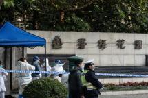 Police officers and medical staff members wearing personal protective equipment (PPE) are seen outside a residental area that is under restrictions following a recent coronavirus outbreak in Shanghai on November 26, 2021. – that is under restrictions following a recent coronavirus outbreak in Shanghai on November 26, 2021. (Photo by AFP)