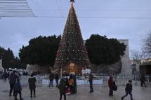 Visitors pose for pictures with the Christmas tree in Manger Square outside the Church of the Nativity, revered as the site of Jesus Christ's birth, ahead of Christmas in the biblical city of Bethlehem in West Bank on December 23, 2021. Photo: AFP