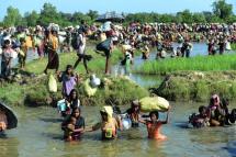 Rohingya refugees walk through a shallow canal after crossing the Naf River as they flee violence in Myanmar to reach Bangladesh in Palongkhali near Ukhia. Photo: AFP