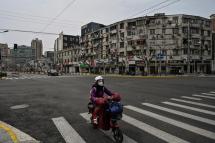 A woman drives a scooter down a quiet street in Yangpu distric, in Shanghai on March 28, 2022. Photo: AFP