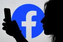 In this photo illustration, a person looks at a smart phone with a Facebook App logo displayed on the background, on August 17, 2021, in Arlington, Virginia
