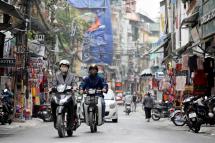 People wearing face masks ride motorbikes on a street in Hanoi, Vietnam. Photo: EPA