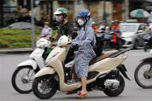 A woman wears long clothing to protect herself from the heat while riding a motorcycle along a street in Hanoi, Vietnam 08 May 2023. Photo: EPA.
