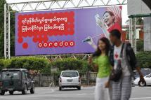 A couple walk pass near 'Ooredoo' telecom company advertising at a roadside in Yangon, Myanmar. Photo: EPA