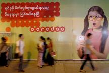 Myanmar people pass by a 'Ooredoo' telecom company advertising in downtown Yangon, Myanmar. Photo: EPA