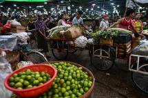 Workers transport fresh vegetables and fruits at a whole sale market in Yangon. Photo: Ye Aung Thu/AFP