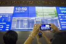 A visitor takes a photo of a large video screen displaying stock prices at the Yangon Stock Exchange in Yangon. Photo: Ye Aung Thu/AFP